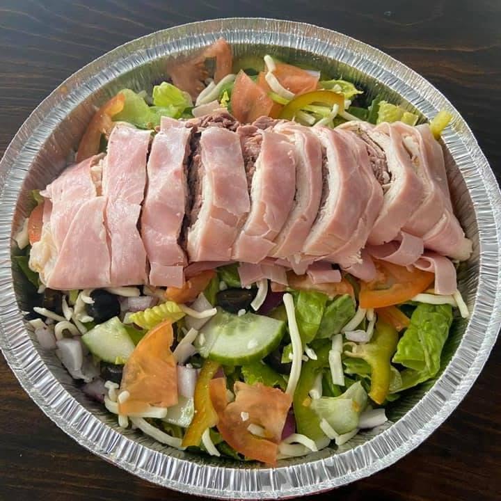 A loaded antipasto salad piled with ham, roast beef, cheese, tomato, cucumber and peppers