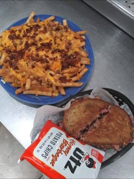 Bacon cheese fries and a hot grilled reuben with a bag of chips